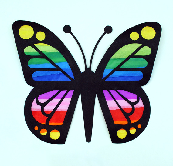 Mariposa de cartulina negra con las alas decoradas con tiras de papel de colores